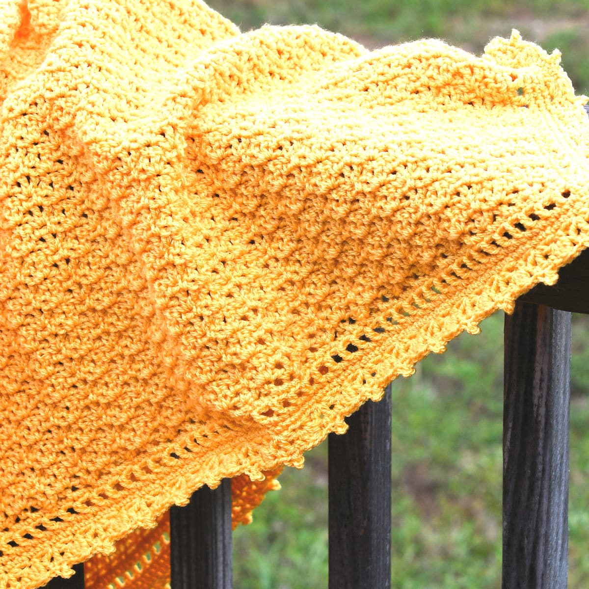 Crocheted Baby Blanket draped on wooden fence