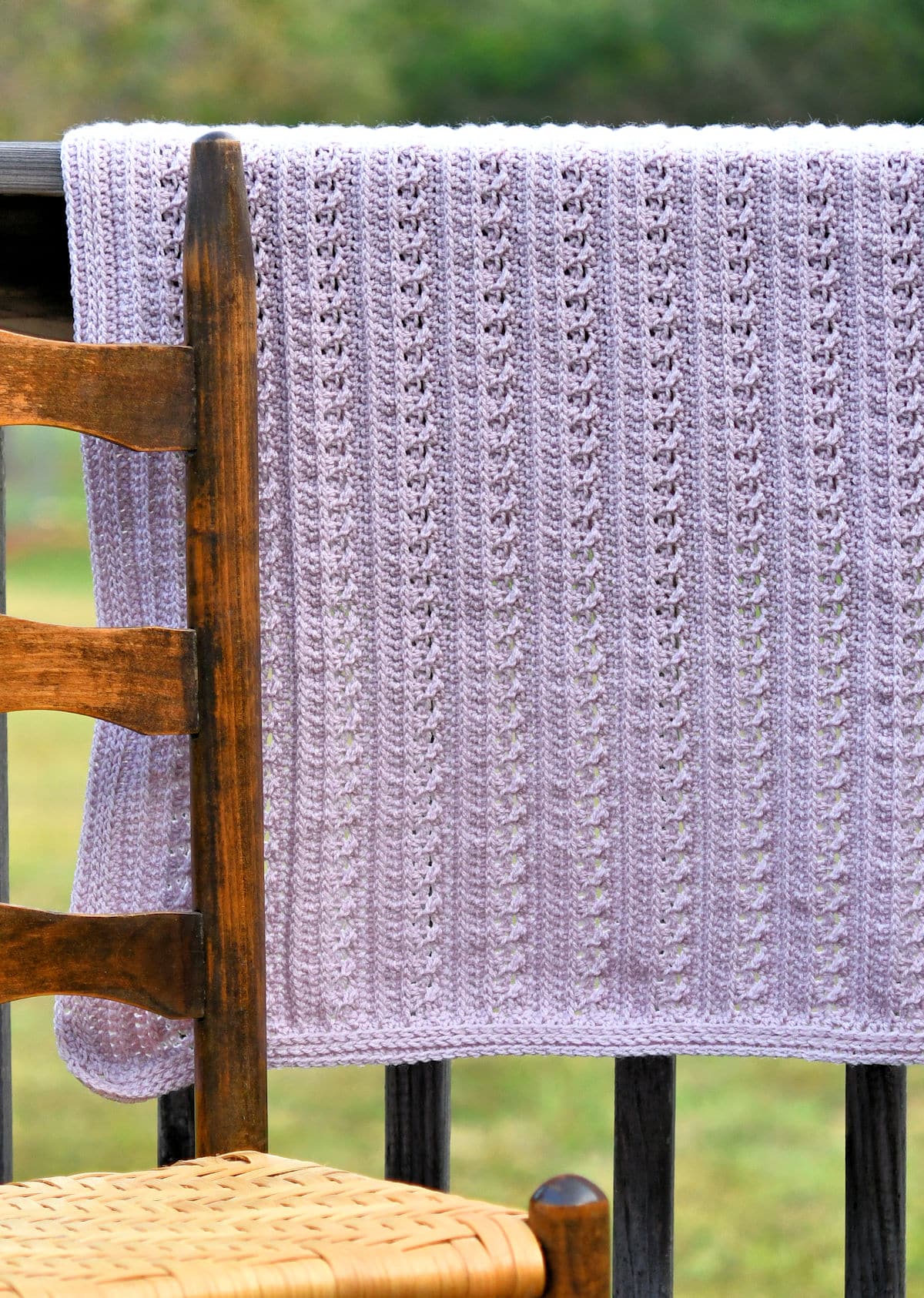 lightweight delicate lace baby blanket draped over a wooden fence